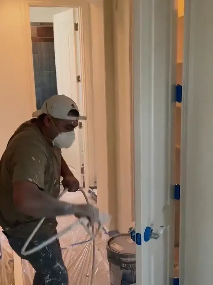 V&S painter spraying interior trim with a mask and drop cloths in place