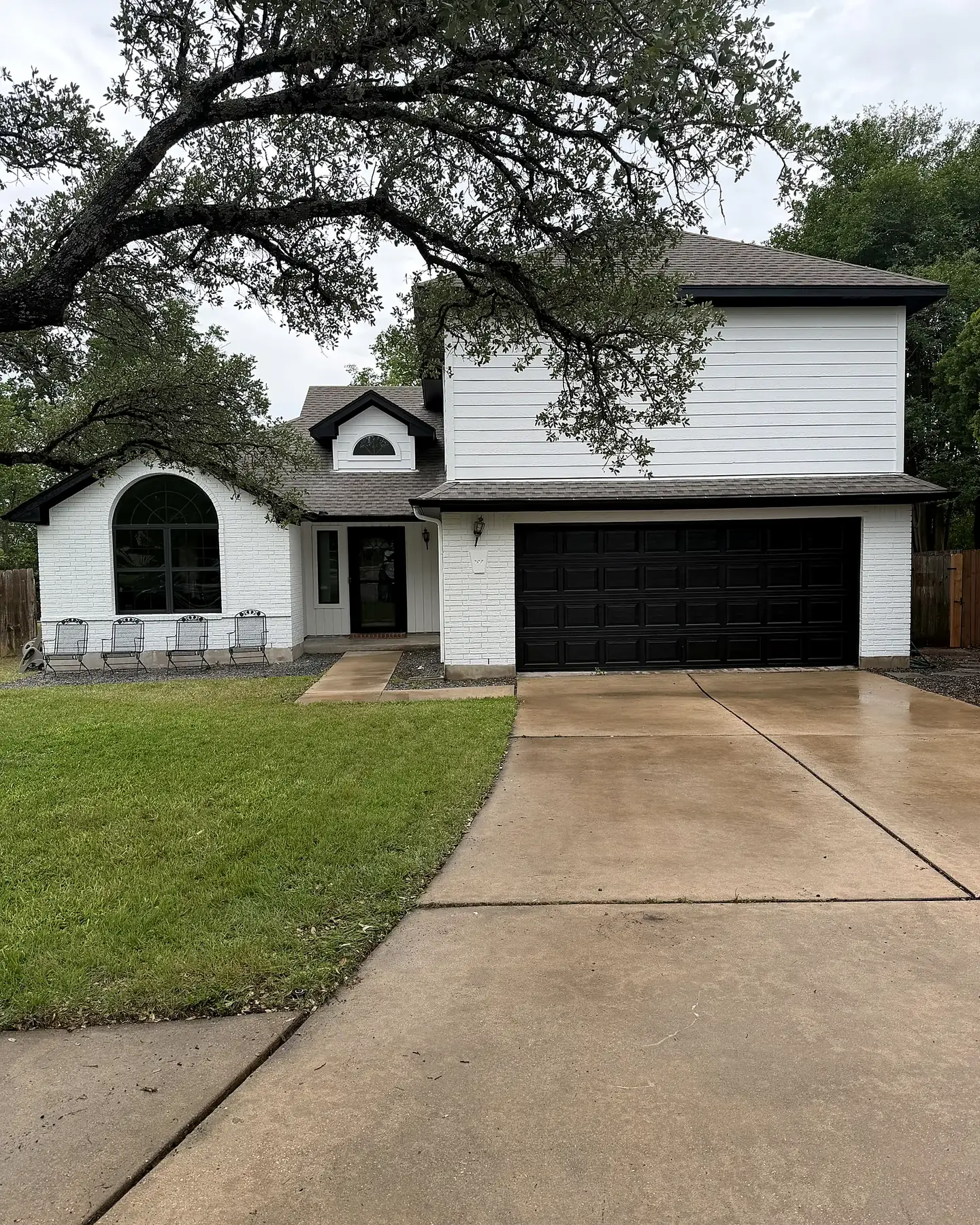 Two-story home painted bright white with a black garage door