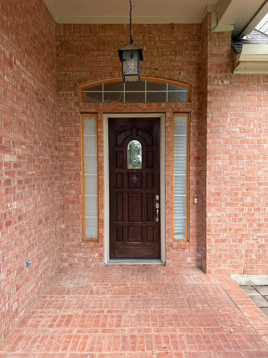 Arched brick front entry before painting, sidelights masked with tape, Austin TX