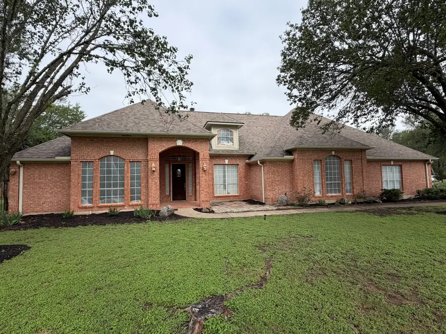 Red brick Austin home before exterior painting, windows masked in plastic
