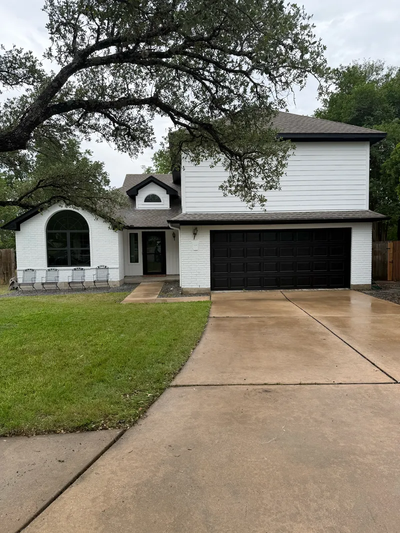 Two story Austin home repainted bright white with black garage door by V&S Services
